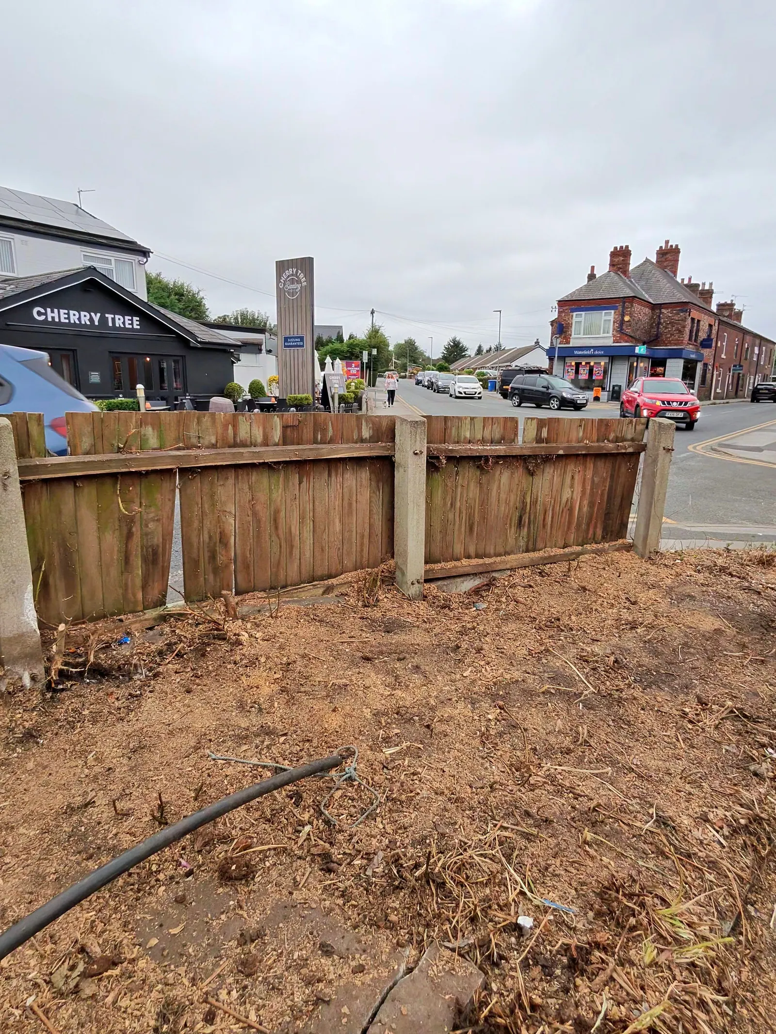 Timber boundary fence beside a cleared area of soil near a road