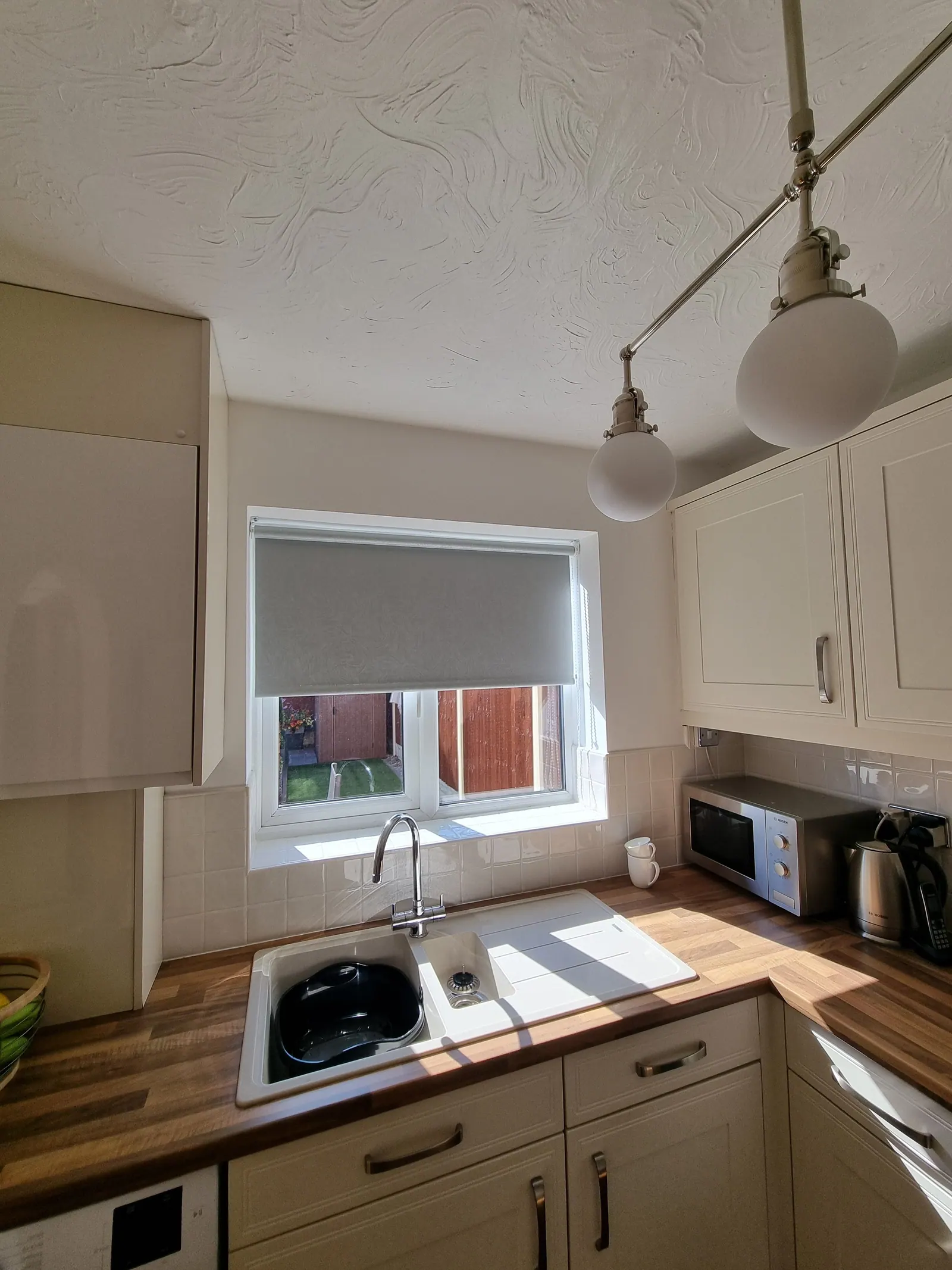 Bright kitchen with cream units, wood-effect worktops and smooth painted walls