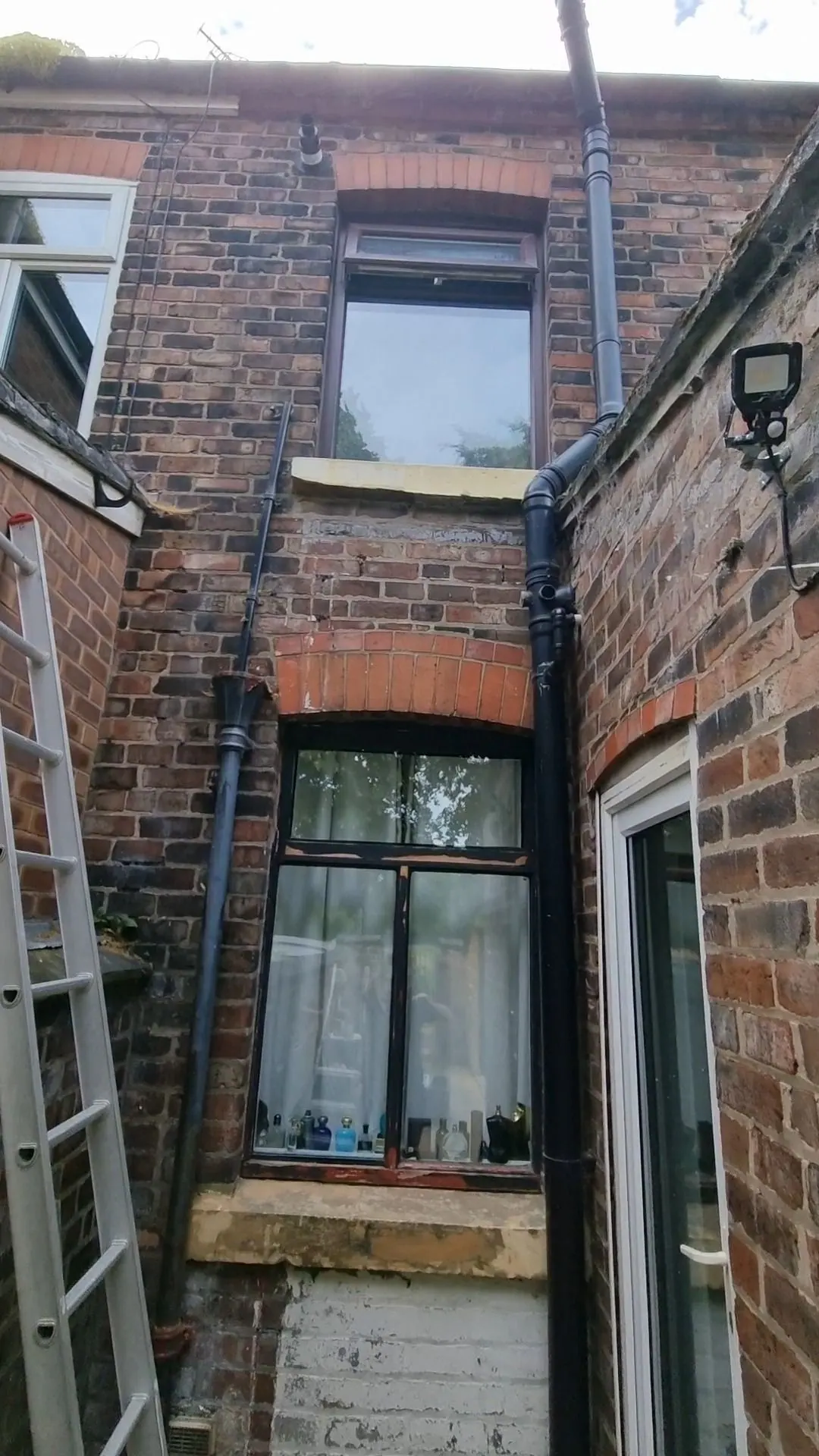 Rear brick wall of a house with a ladder in place during exterior work