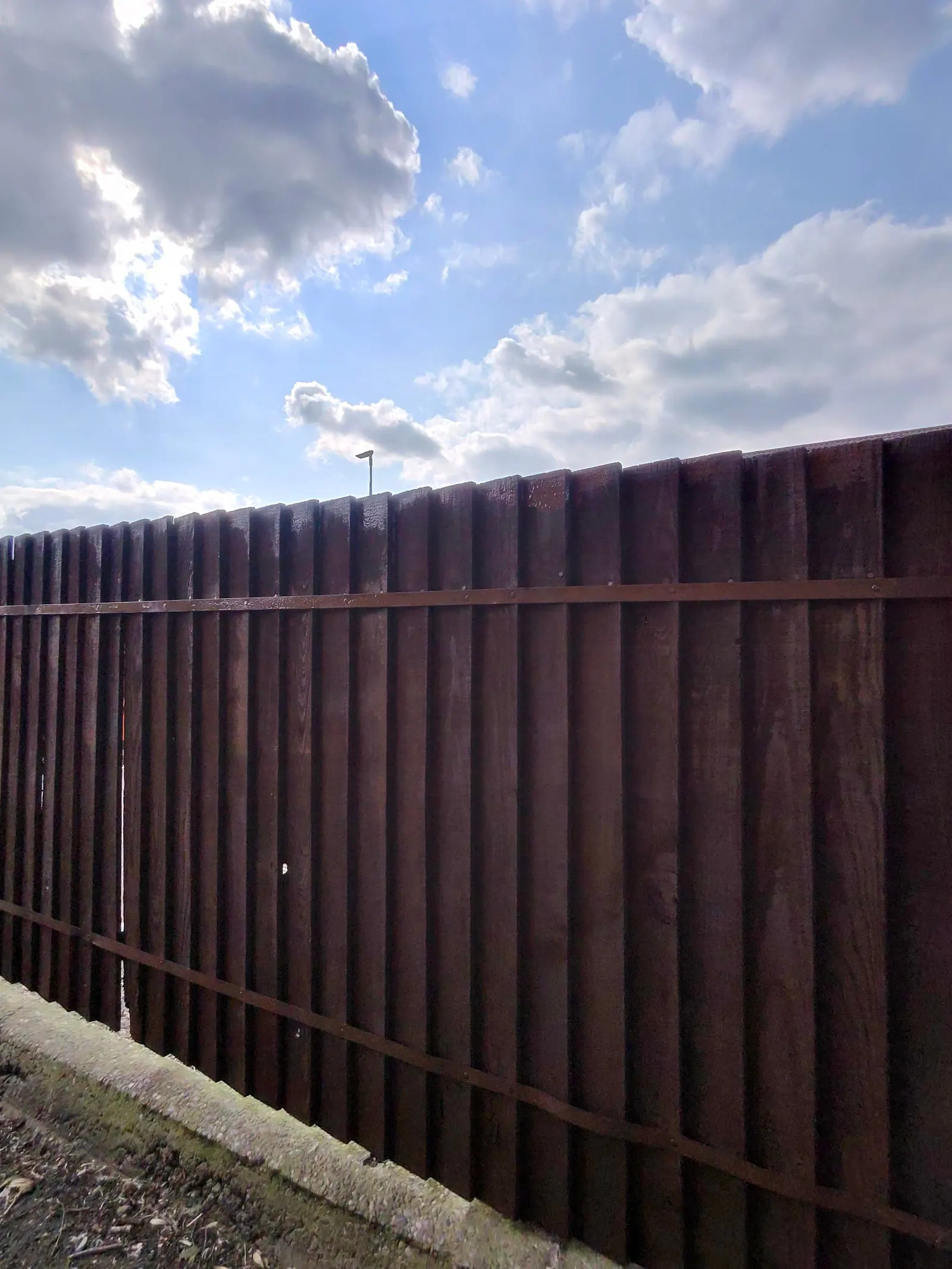Long run of dark brown painted fence panels