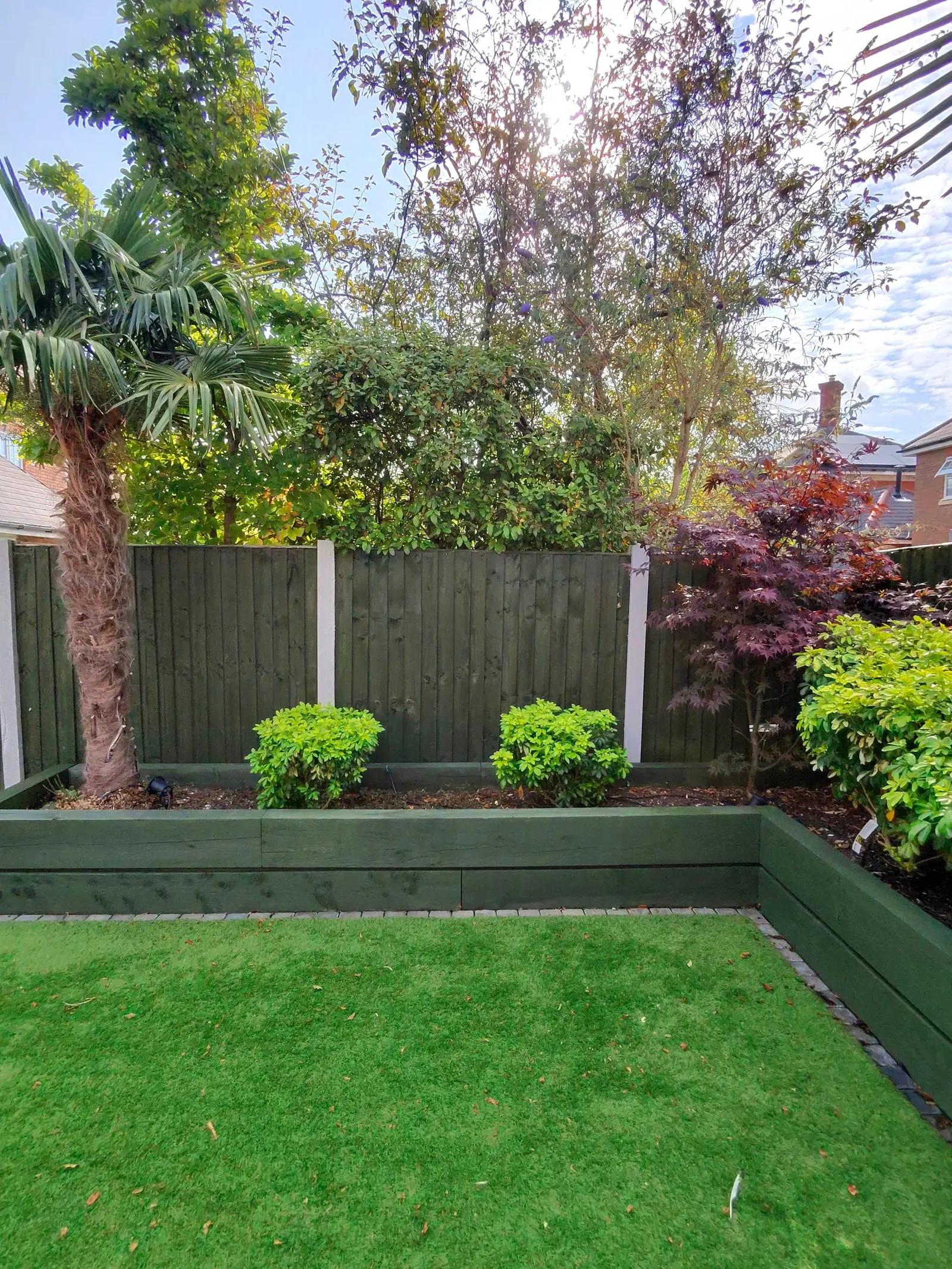 Back garden with a newly painted green fence and matching raised beds