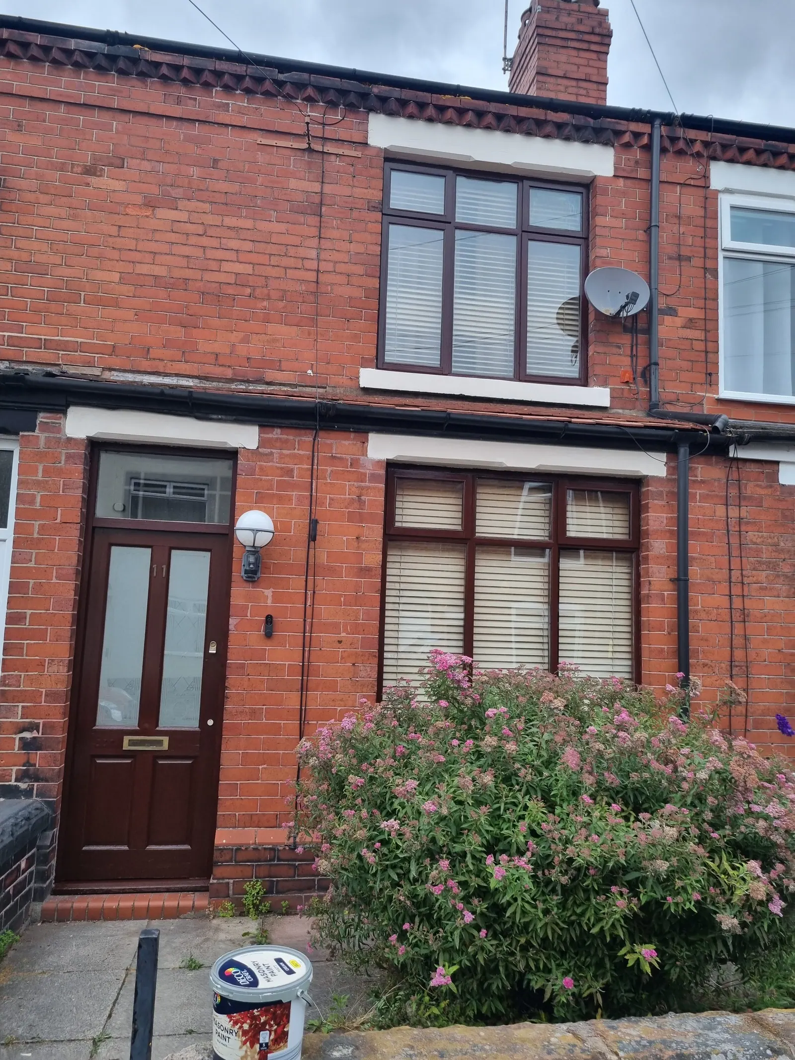 Front of a red-brick terraced house with a paint tin by the path
