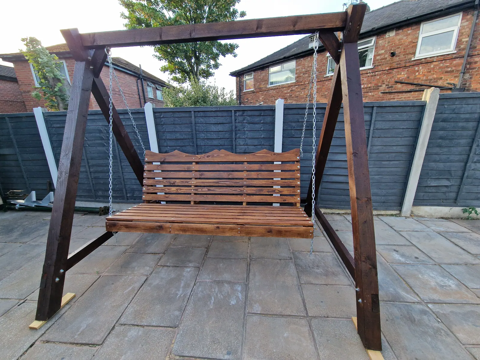 Dark stained timber swing seat on a patio