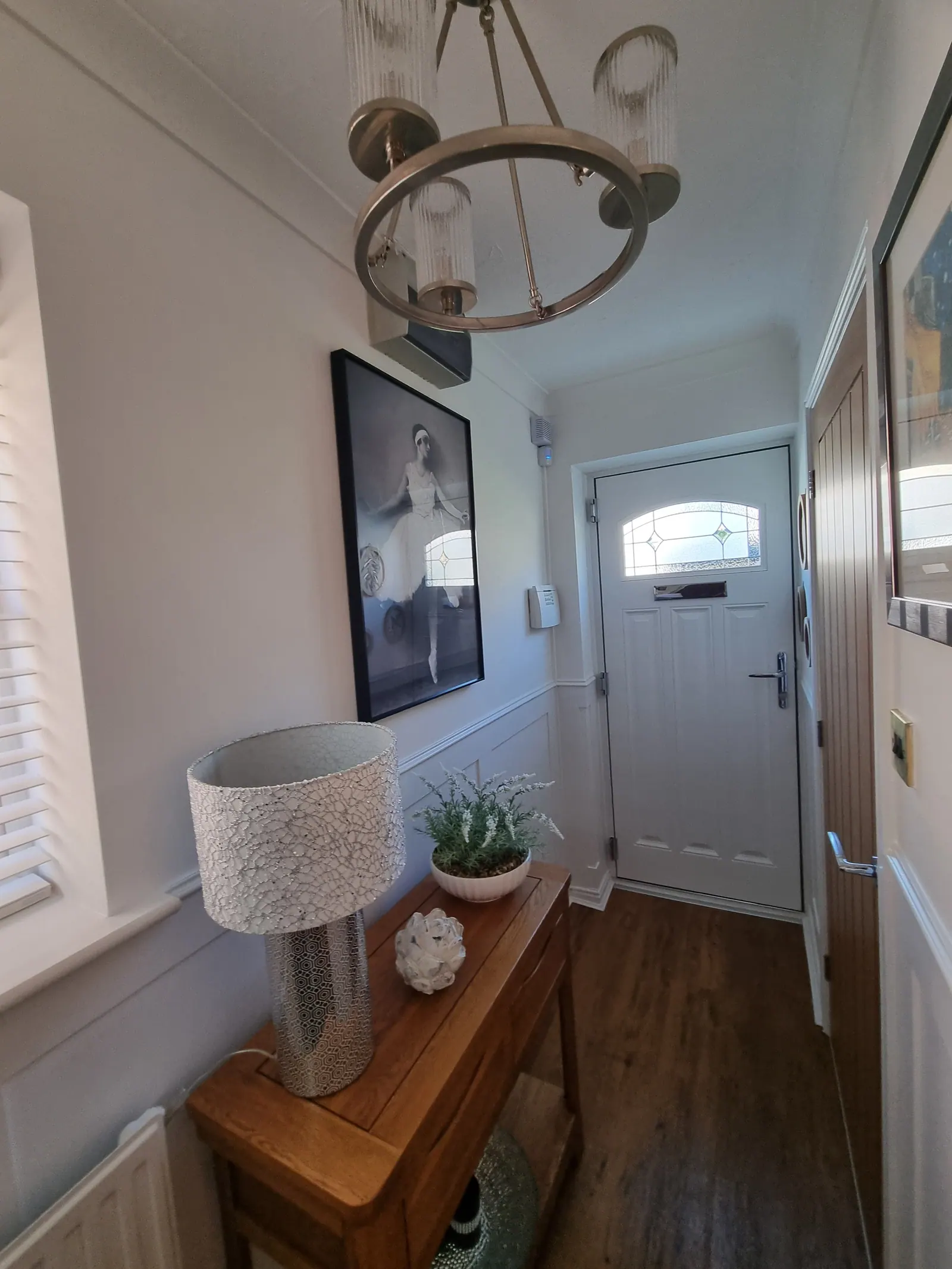 Hallway with a pendant light, framed artwork and panelled walls