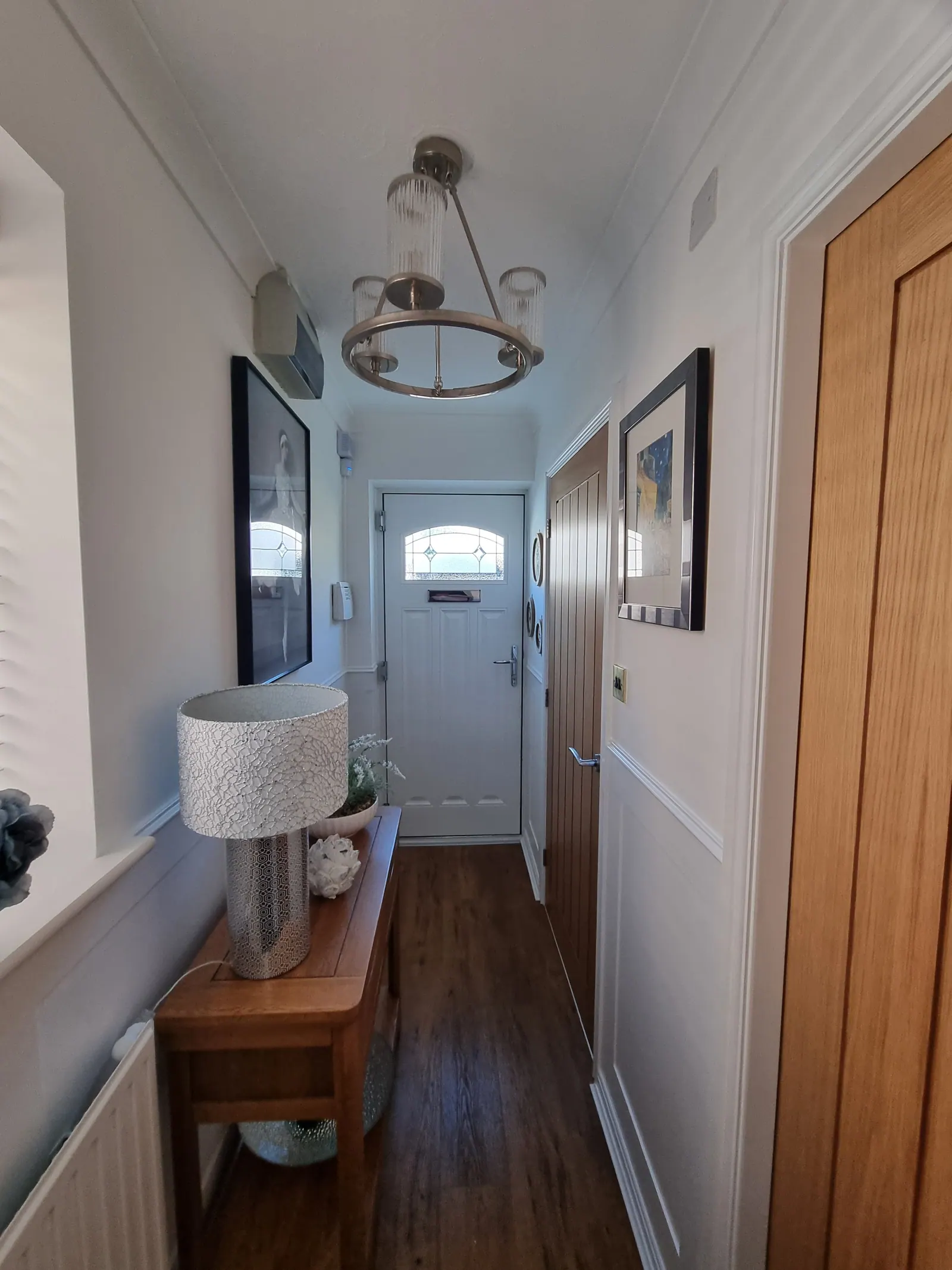 Hallway with panelled walls leading to a white front door