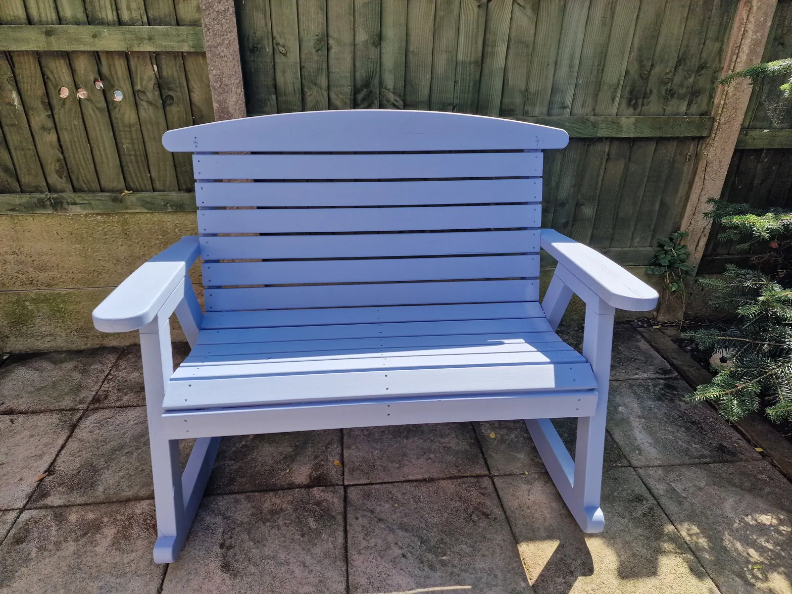 Garden bench freshly painted lilac on a patio