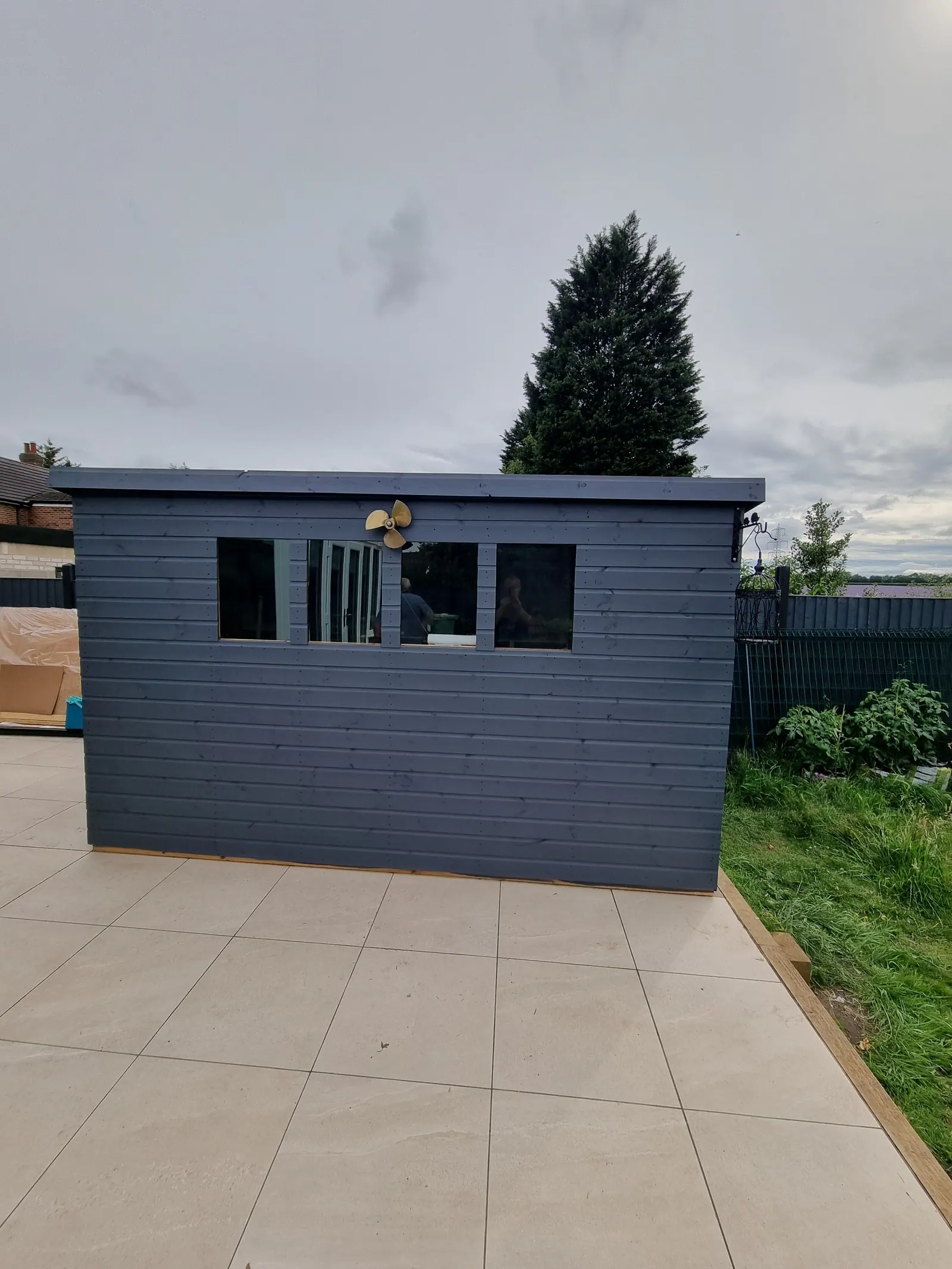 Large grey-painted timber garden building on a tiled patio