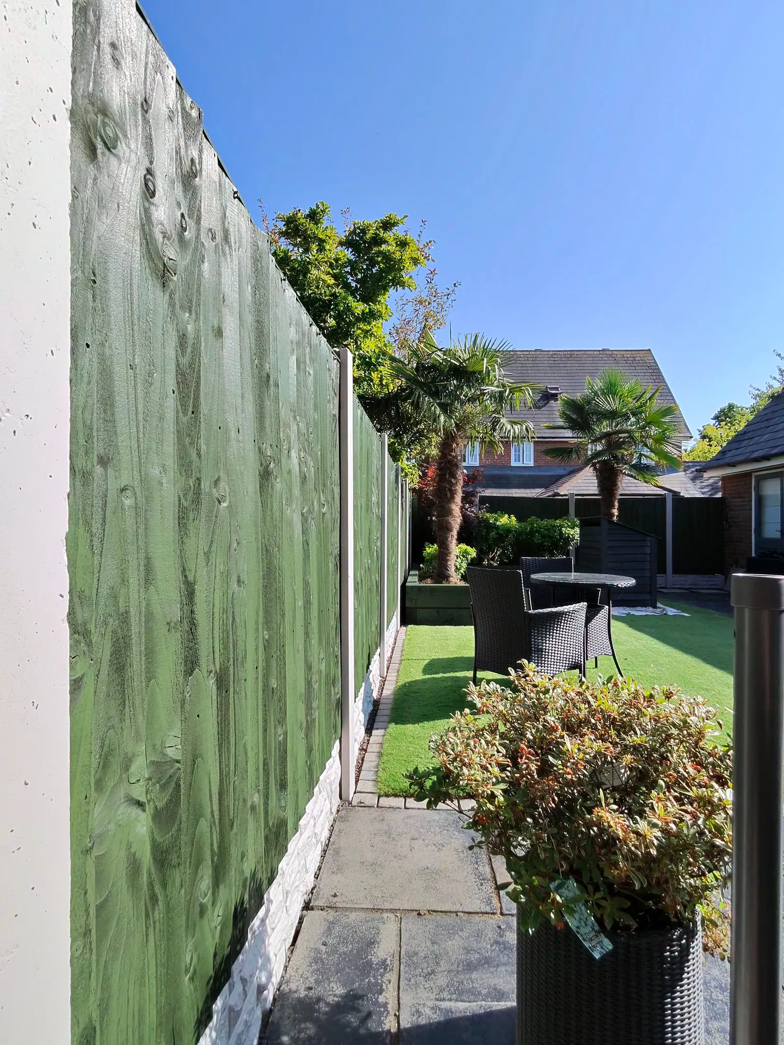 View along a freshly painted green fence with concrete posts