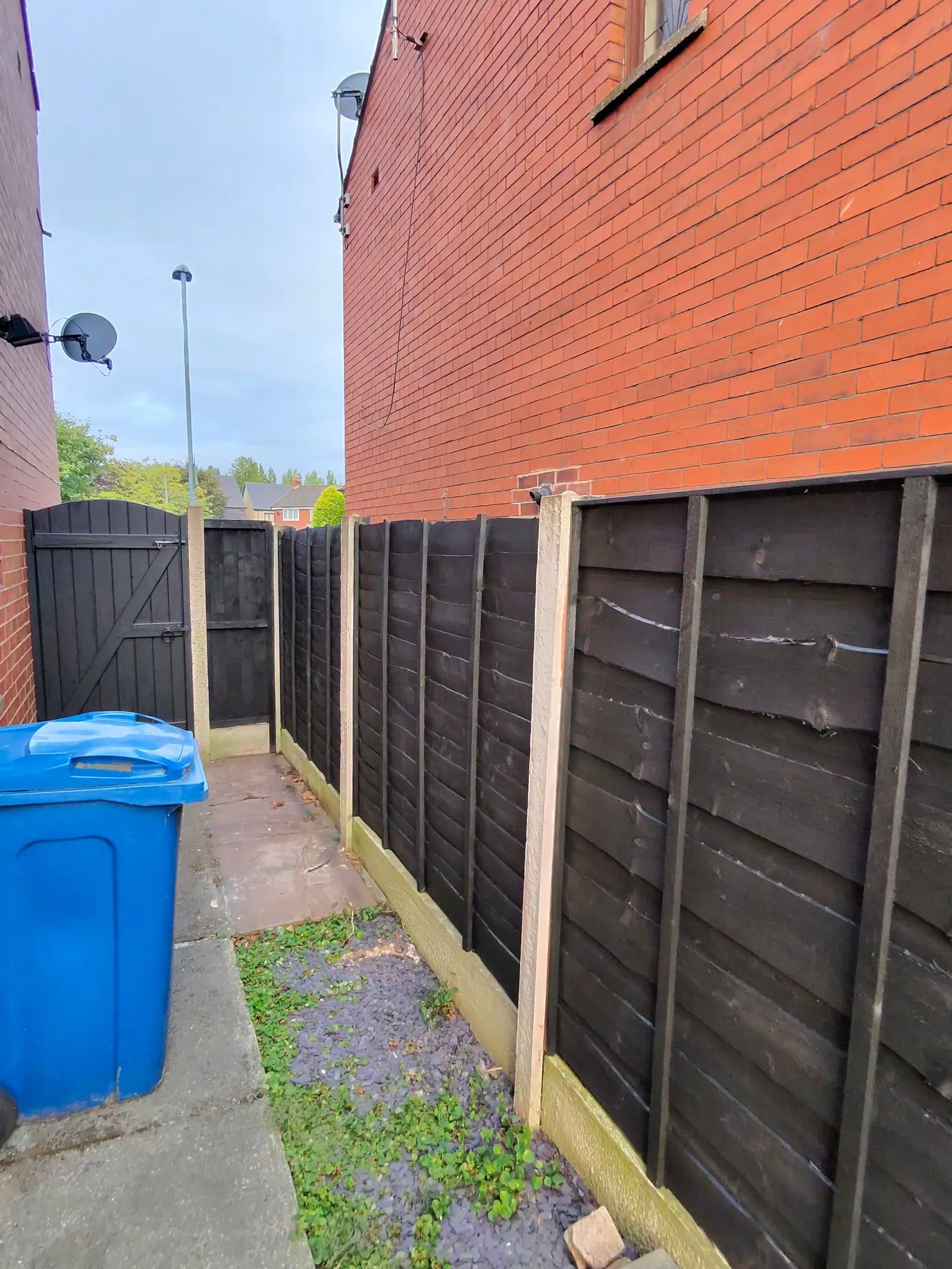Dark painted fence panels along a side passage