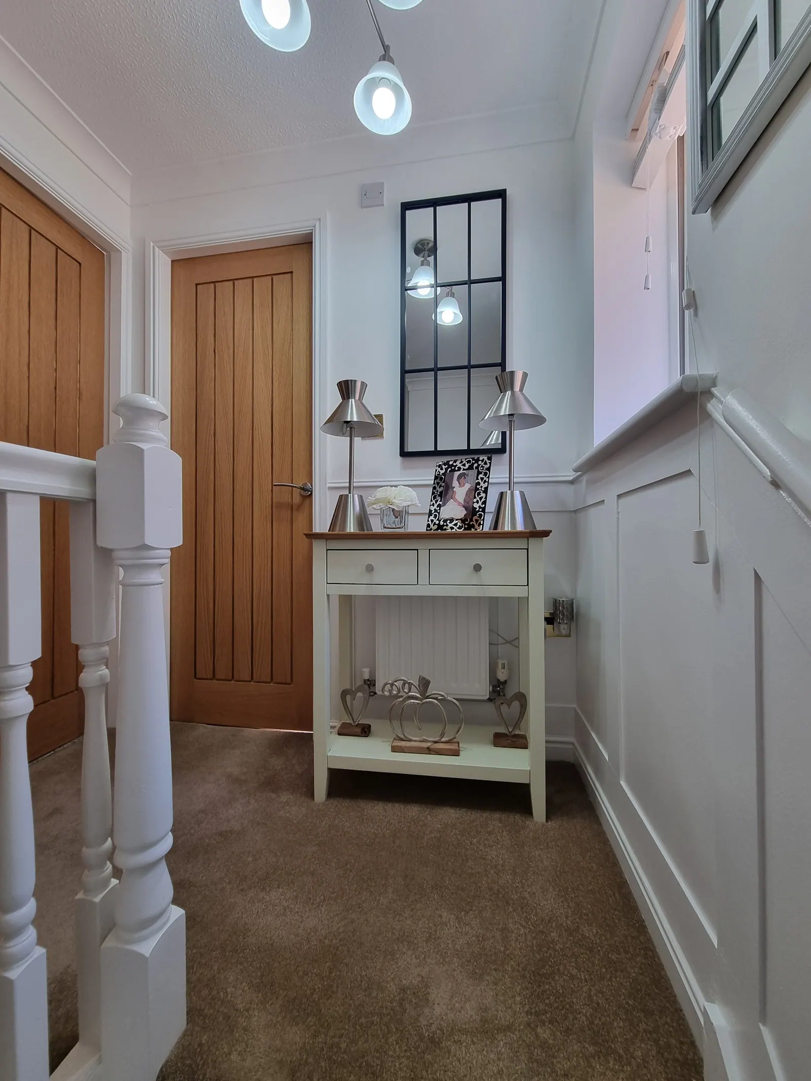 Landing with panelled walls, an oak door and a console table