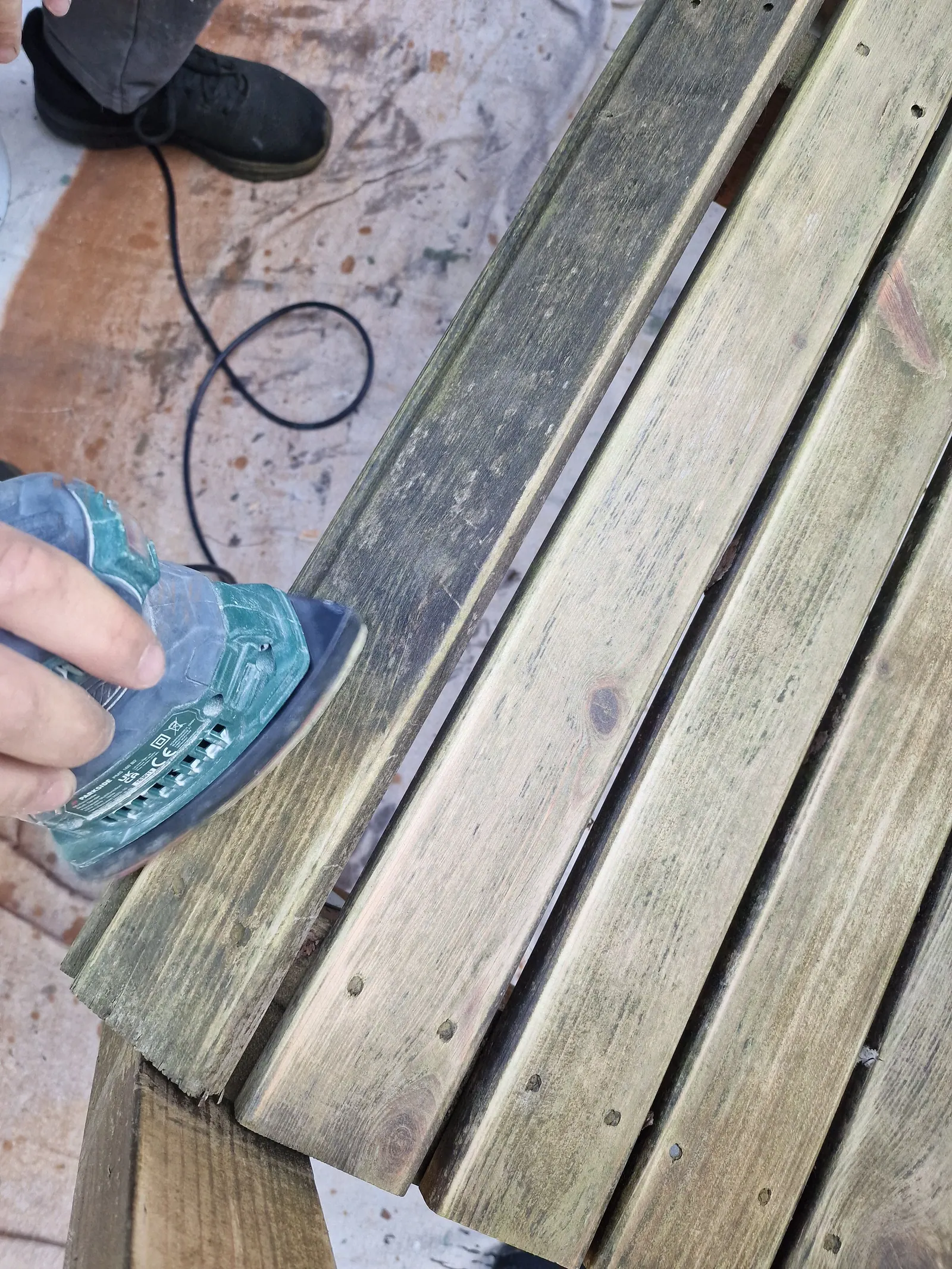 Weathered timber slats being sanded with a power sander